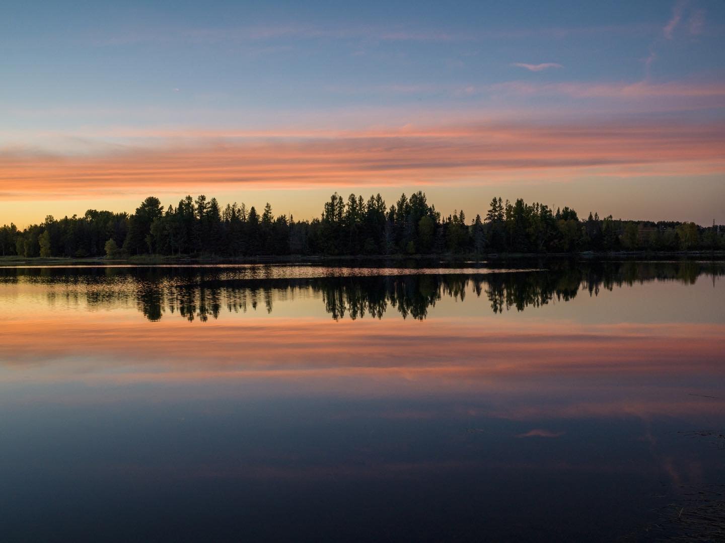 Silhouetted in the fading light after sunset, the shoreline of Flagstaff Lake is banded by low clouds and their reflection in the still lake water. Autumn sunsets provide great graphics! #flagstafflakemaine #autumnsunsets #orcuttphotography