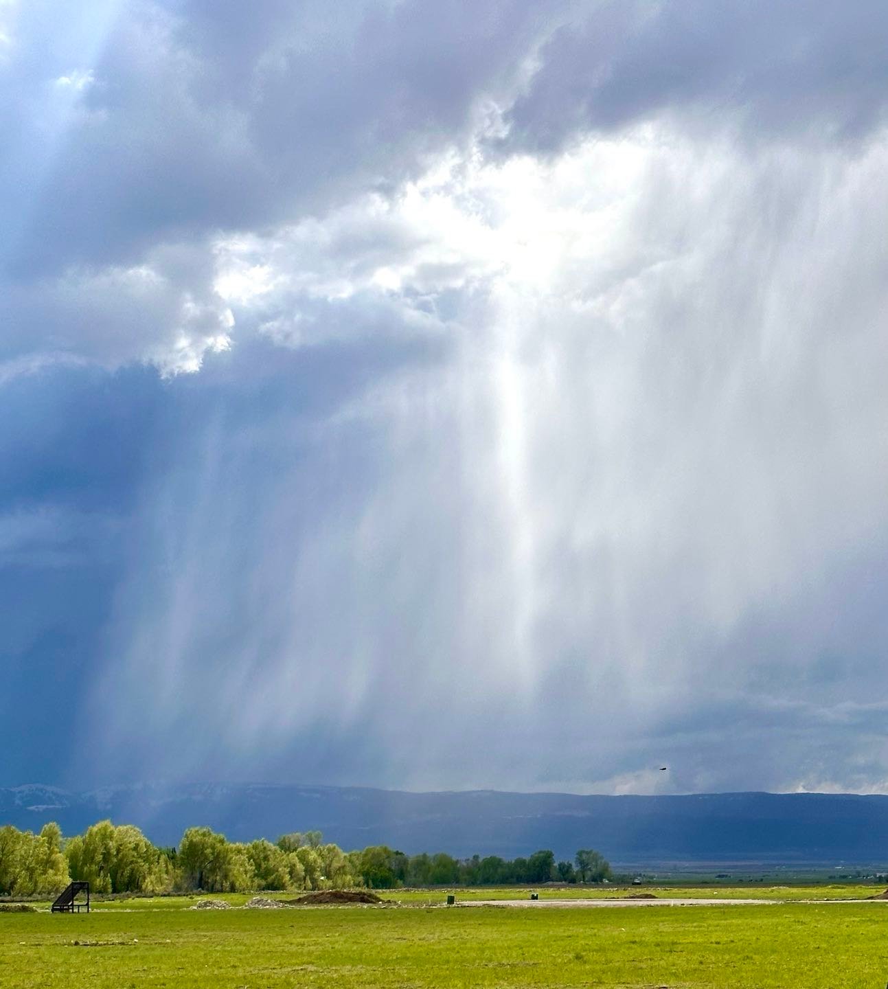 Spring weather in Teton Valley, Idaho. Fields and trees are bright green, and the big dramatic sky is articulated by thunder storms in different places at the same time. We appreciate the rain in Teton Valley, but combined with last winter’s snow melt there is flooding in the low areas.  #tetonvalleyidahospringtimeweather #driggsidaho #thunderstormsintetinvalley #bestofthegemstate #orcuttphotography.danstpeter.com